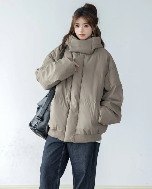 ベージュ/カーキのショートダウンと濃色ジーンズを着用した女性モデルの全身像。黒のショルダーバッグを肩に掛けている。