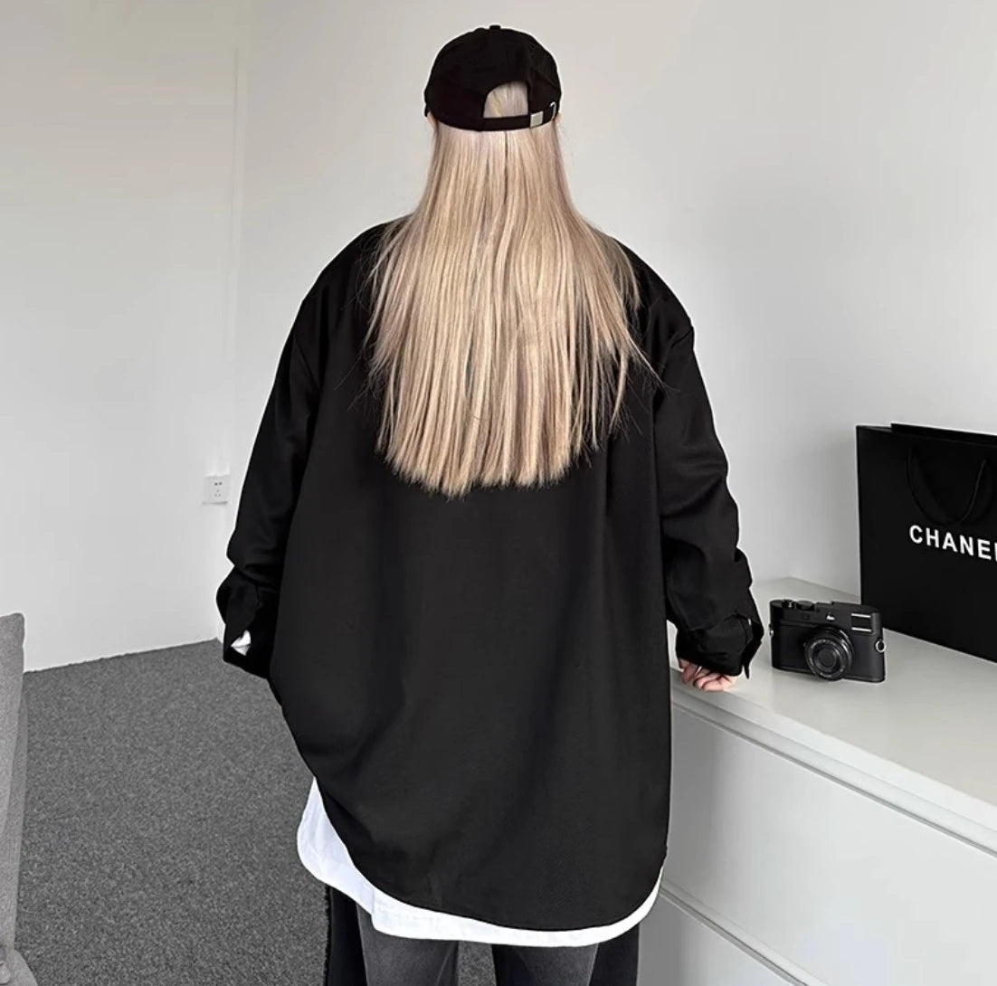 黒のオーバーサイズシャツを着用した後ろ姿。背中は無地のシンプルなデザインで、ヒップが隠れる丈感。