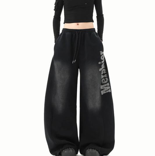 黒のワイドスウェットパンツを着用した全身正面。ウエストのドローコードとサイドの「Mershier」ロゴ。