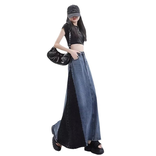 グレーのロングデニムスカートを着たモデル。斜め横向きで、黒いバッグを手に持っている。