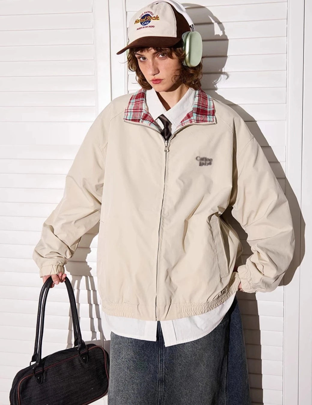 アプリコットカラー側のリバーシブルジャケットを着たモデル。バッグを持って立ち姿。