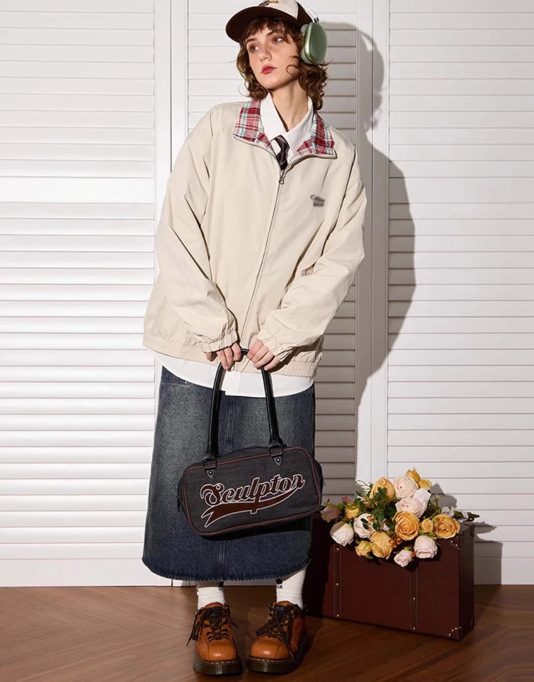 アプリコットカラー側のリバーシブルジャケットを着たモデル。花束とトランクの隣。