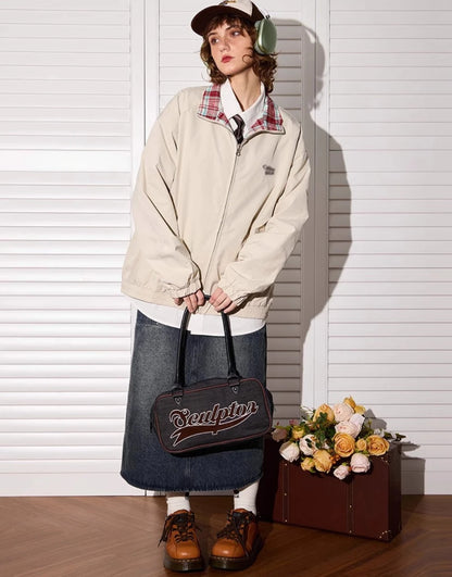 アプリコットカラー側のリバーシブルジャケットを着たモデル。花束とトランクの隣。