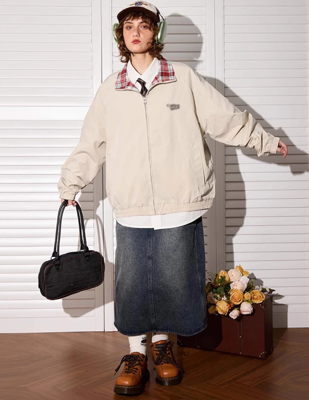 アプリコットカラー側のリバーシブルジャケットを着たモデル。全身、バッグ持ち。