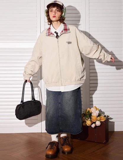 アプリコットカラー側のリバーシブルジャケットを着たモデル。全身、バッグ持ち。