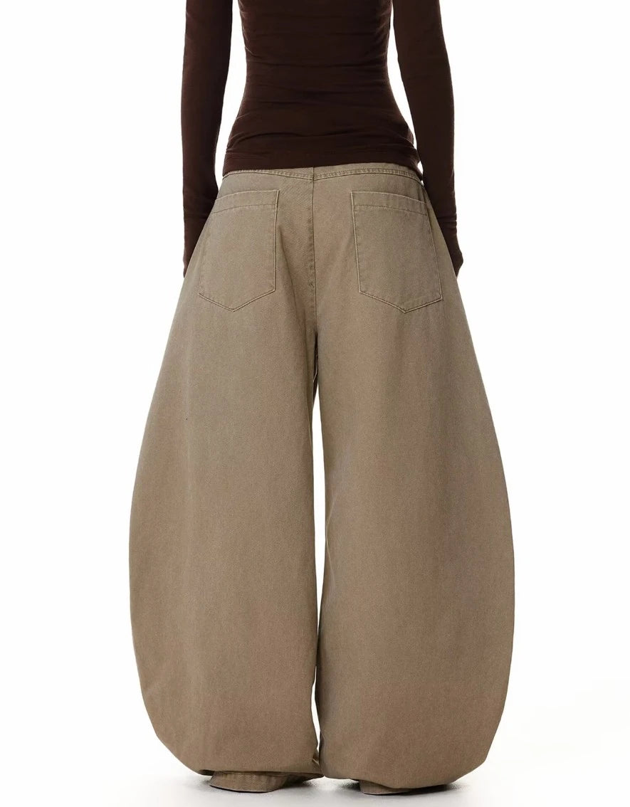 ベージュのバギーパンツを着用した後ろ姿。背面は無地で、ヒップポケットのディテールが確認できる。