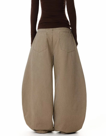 ベージュのバギーパンツを着用した後ろ姿。背面は無地で、ヒップポケットのディテールが確認できる。