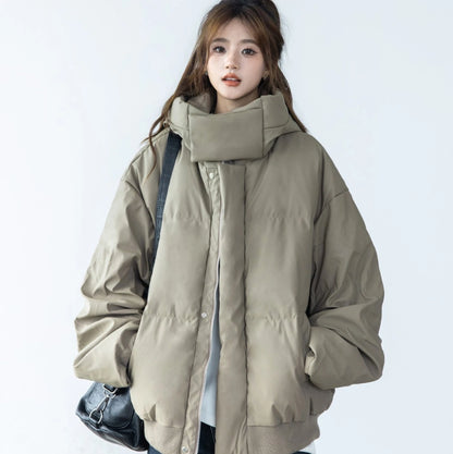 ベージュ/カーキのショートダウンを着たモデルのバストアップ。ハイネックの襟元を立てており、黒いショルダーバッグを着用。