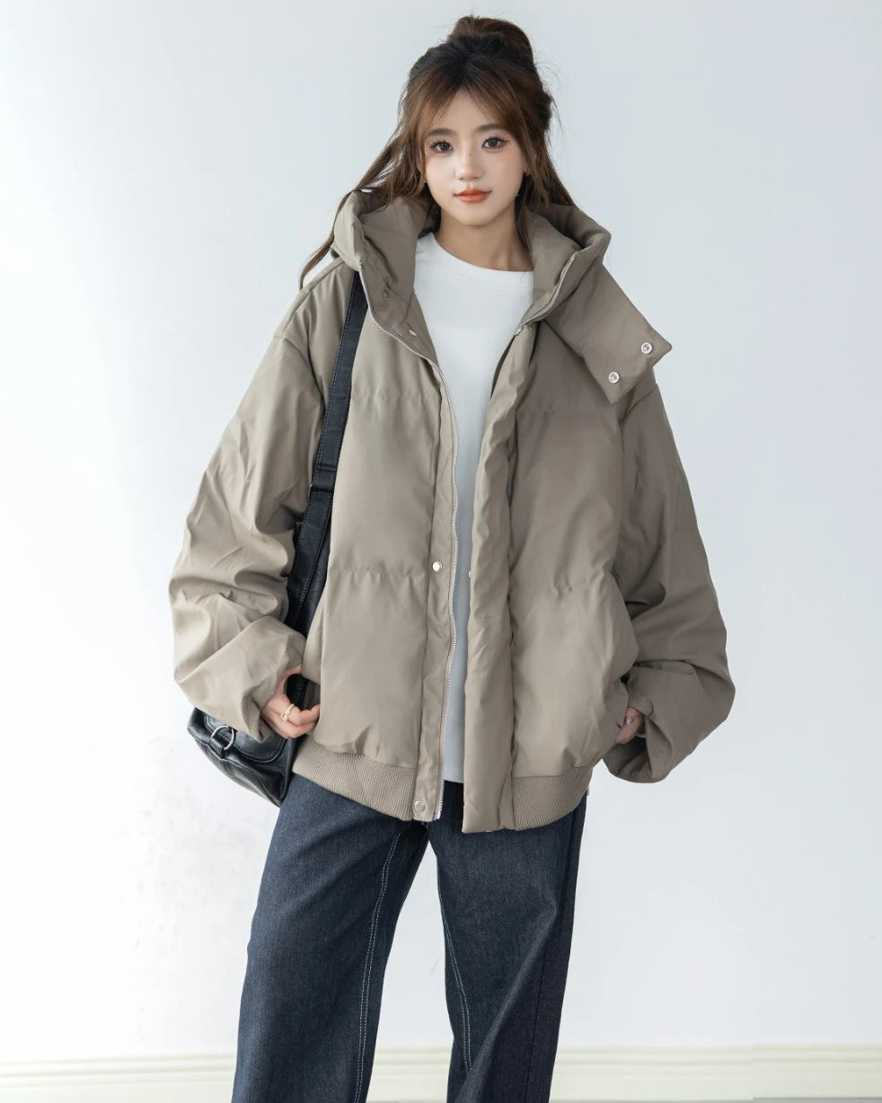 ベージュ/カーキのショートダウンを白Tシャツと濃色ジーンズに合わせた女性モデル。カジュアルな全身コーディネート。