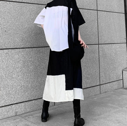 白と黒のバイカラーシャツを着たモデルの全身後ろ姿。ボトムスの裾も白黒のデザイン。