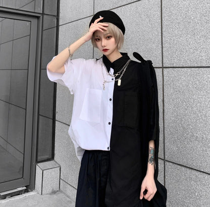 白と黒のバイカラーシャツを着たモデル。手で帽子のつばを押さえるポーズ。