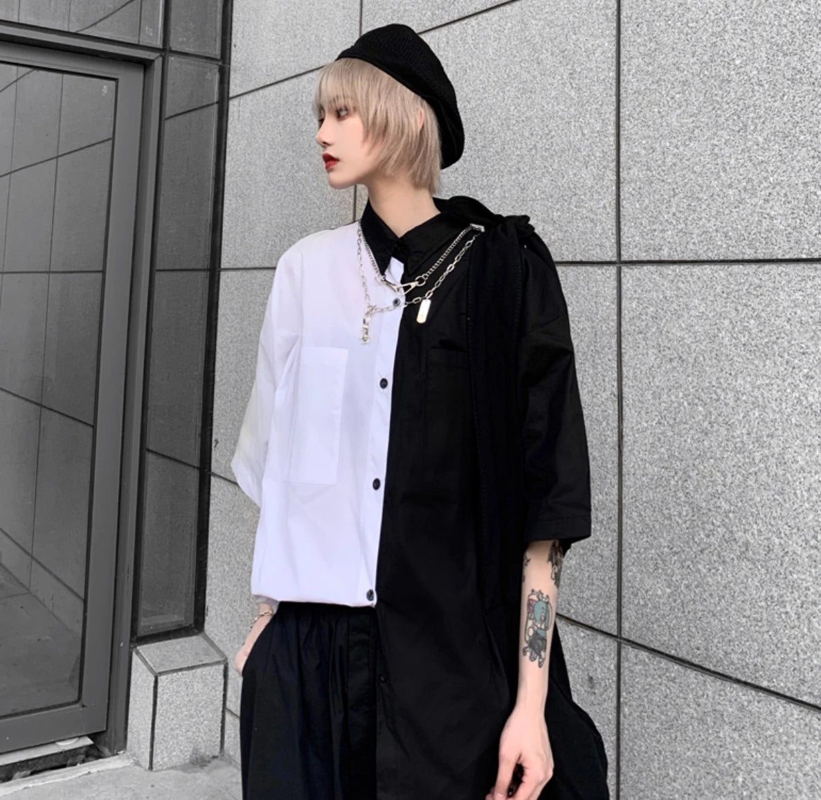 白と黒のバイカラーシャツを着たモデル。横を向き、視線を外したポーズ。