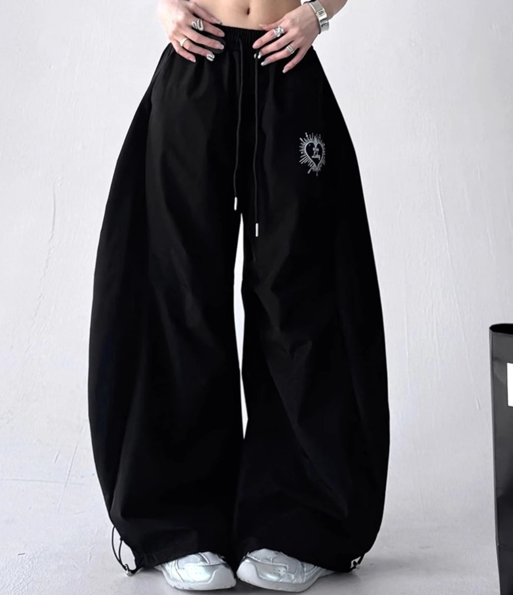 黒いバルーンパンツを着用した正面からの全身写真。ゆったりとしたシルエットで、裾のドローコードが特徴。