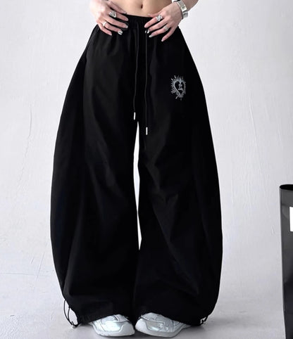 黒いバルーンパンツを着用した正面からの全身写真。ゆったりとしたシルエットで、裾のドローコードが特徴。