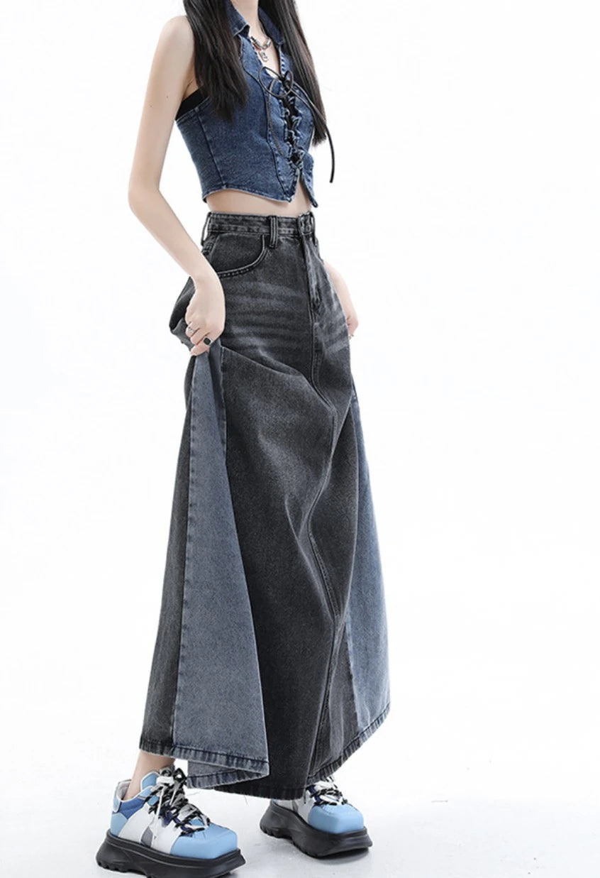 黒のロングデニムスカートを着たモデル。スカートの両端を指でつまみ、生地の広がりを見せるポーズ。