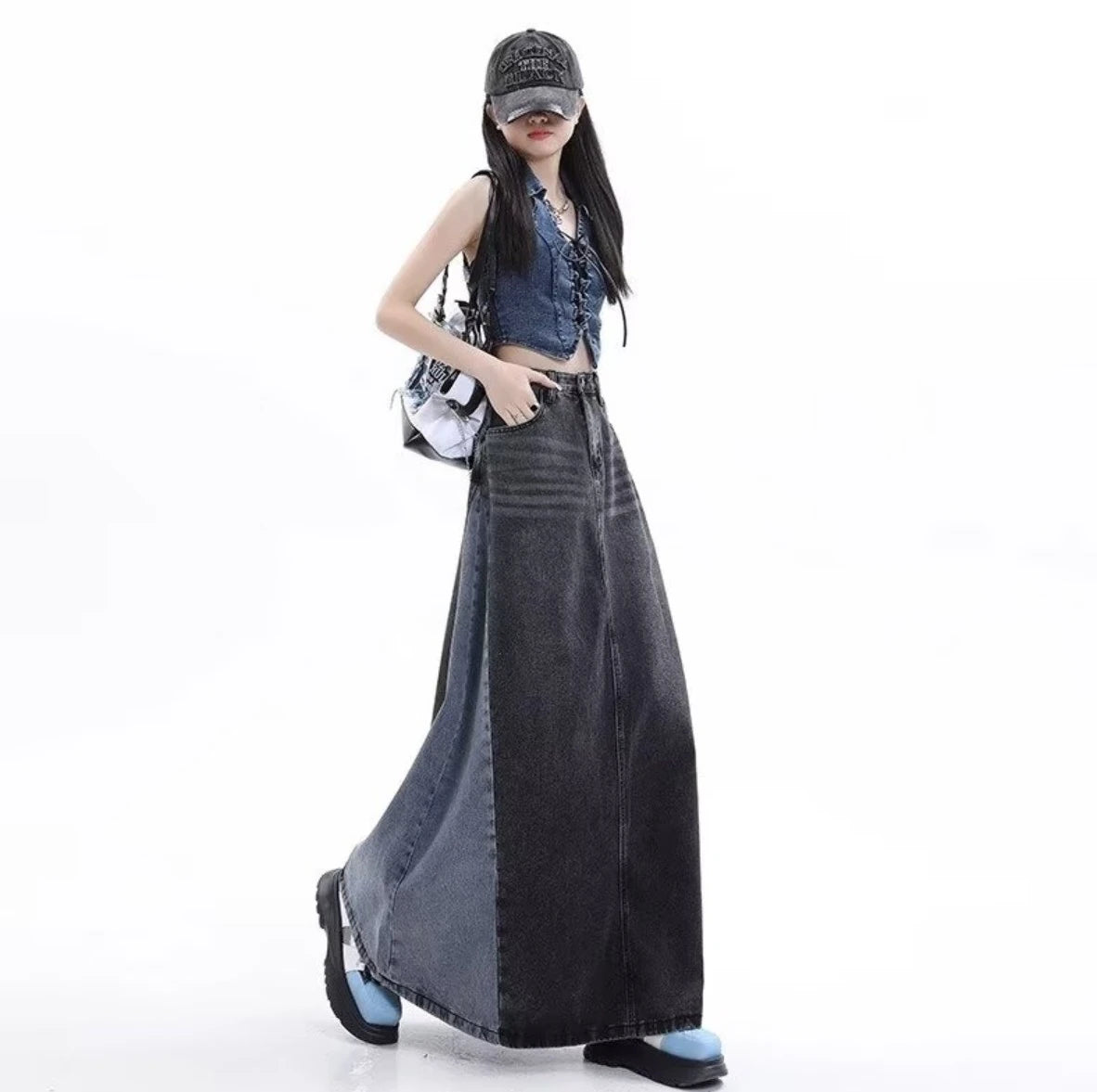 黒のロングデニムスカートを着たモデル。キャップを被り、白いバッグを肩にかけてポケットに手を入れたポーズ。