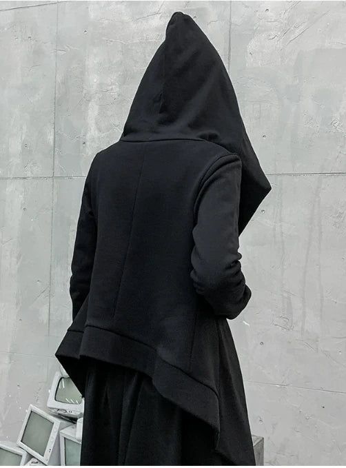 黒の変形フード付きアウターを着たモデルの後ろ姿。大きなとんがりフードのシルエット。