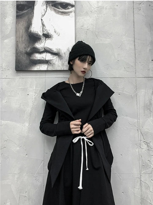 黒の変形フード付きアウター。フードを下ろして大きな襟のように見せている。ニット帽着用。