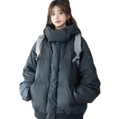 黒のハイネックショート丈ダウンジャケットを着用し、グレーのリュックを背負った女性モデル。ポケットに手を入れた全身像。