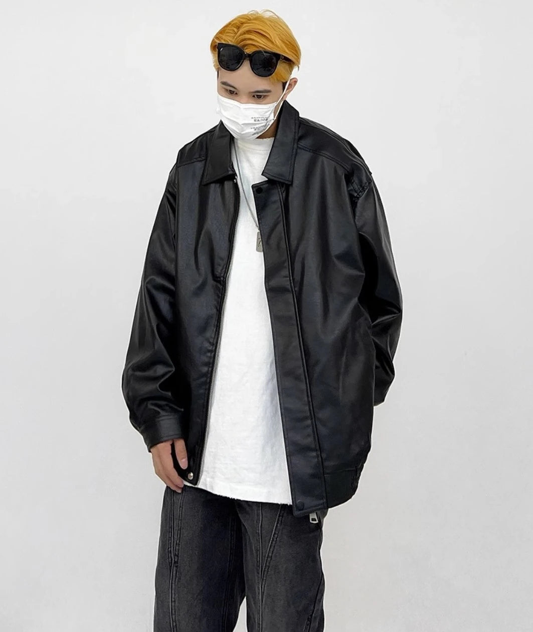 黒のオーバーサイズレザージャケットを白Tシャツに着用した男性モデル。マスクとサングラス。