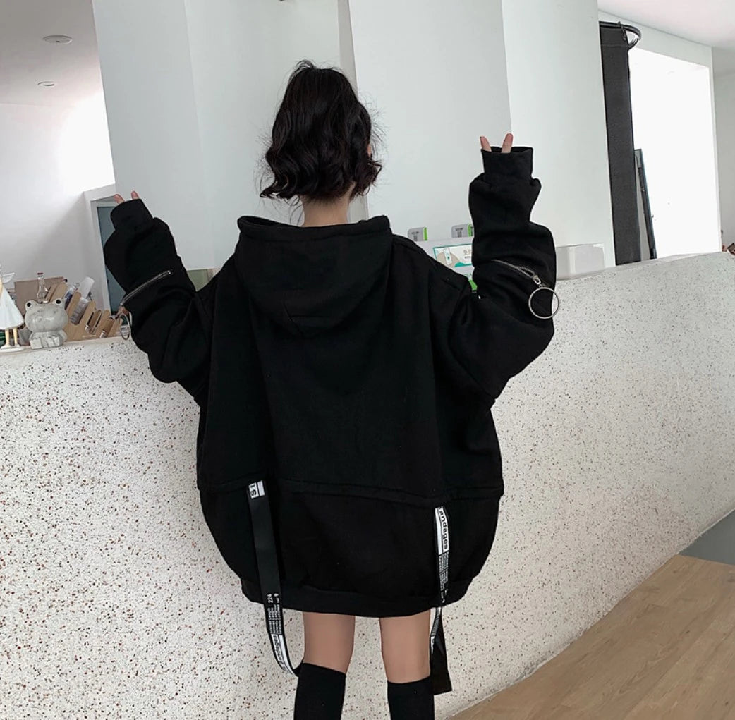 黒のオーバーサイズパーカーを着たモデルの後ろ姿。両手でピースサインを掲げている。