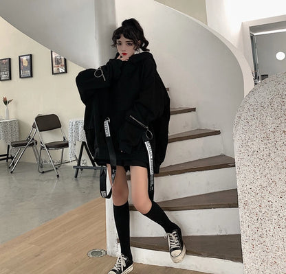 黒のオーバーサイズパーカーを着たモデル。螺旋階段の白い柱に寄りかかる全身ショット。