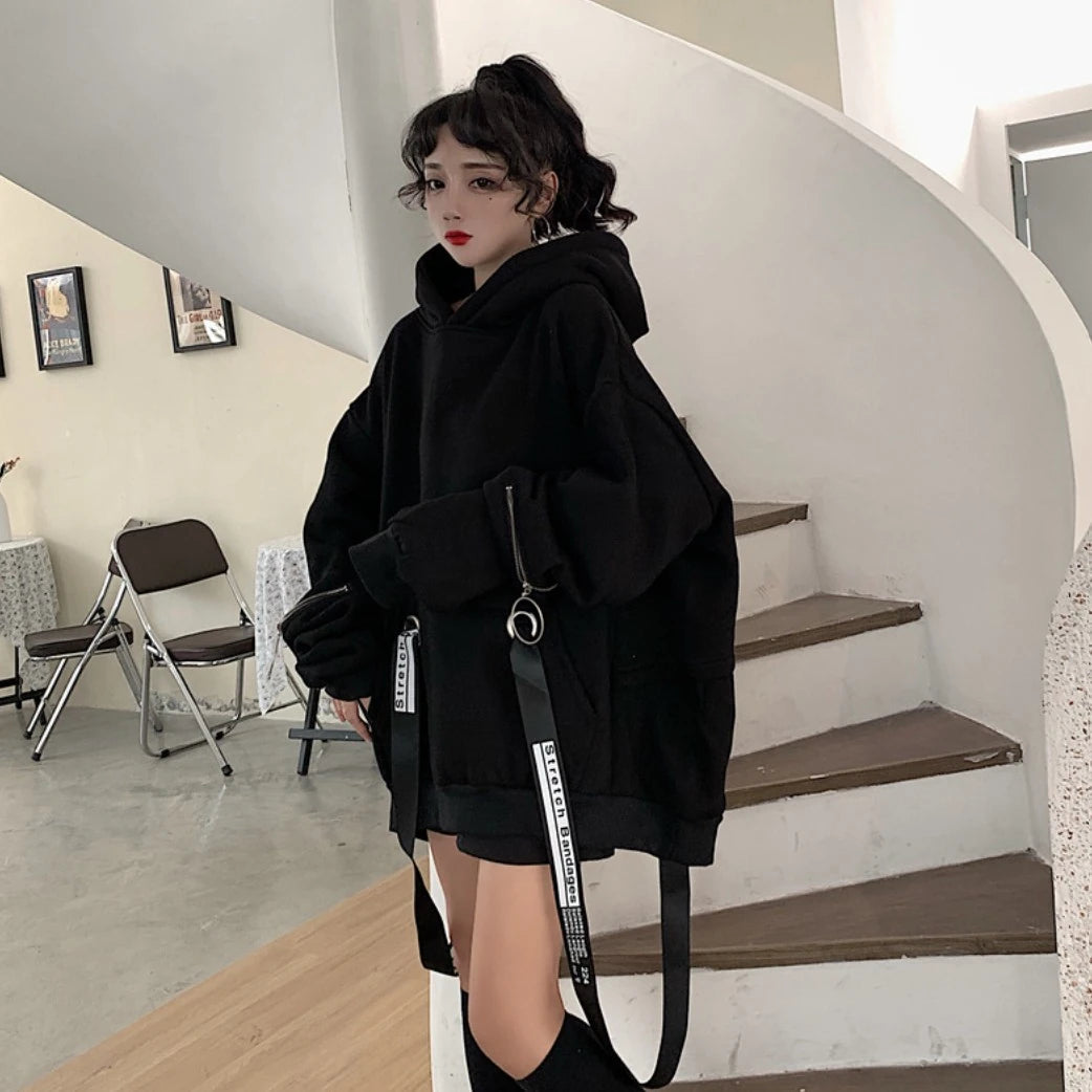 黒のオーバーサイズパーカーを着たモデル。階段の前で立ち、少し斜めを向いている。