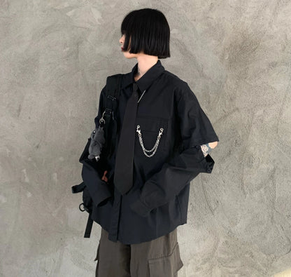 黒のネクタイ付きシャツを着たモデル。横向きで、袖のボタンを外して肌を見せている。