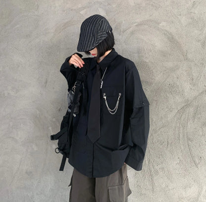 黒のネクタイ付きシャツを着たモデル。ストライプのキャスケットを被り、うつむくポーズ。