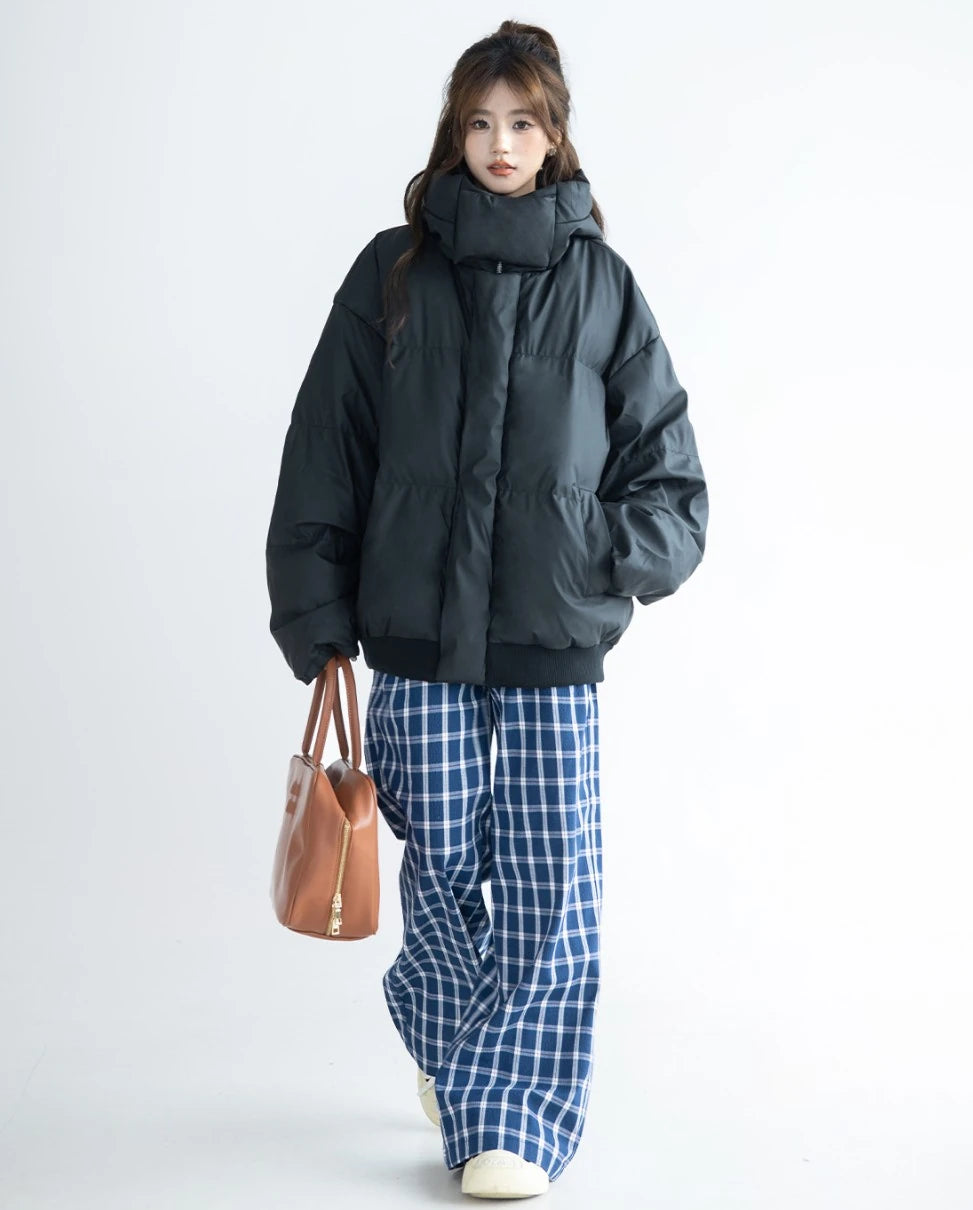 黒のダウンジャケットに青と白のチェック柄ワイドパンツを合わせ、茶色のレザートートバッグを持ったモデルの全身。