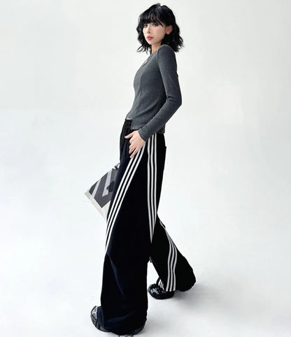 黒のワイドパンツを着用し、俯いたポーズ。パンツのゆったりとしたドレープ感と、ルーズな着こなし。