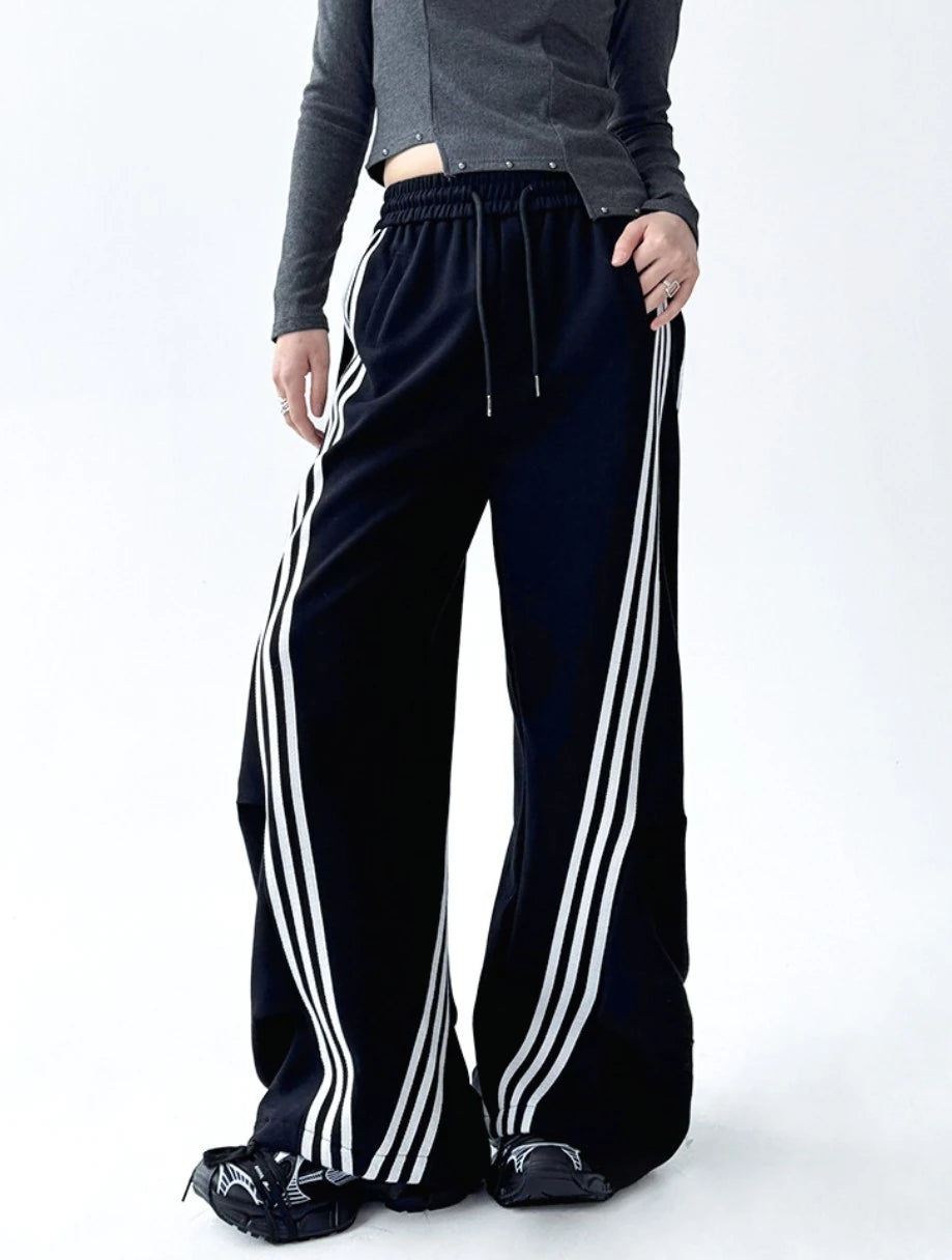 黒ワイドパンツのウエストとドローコードのクローズアップ。モデルが紐に触れる仕草で、ウエストディテールを強調。