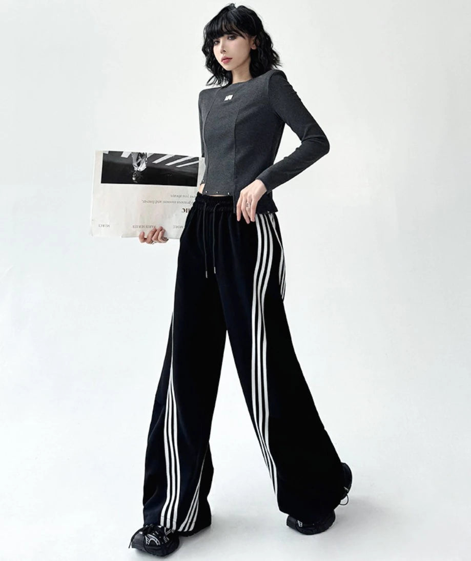 3本ライン入りワイドパンツを着用した全身写真。片手に紙袋を持ち、ストリートカジュアルな雰囲気を演出。