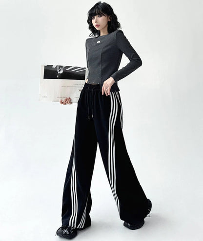 3本ライン入りワイドパンツを着用した全身写真。片手に紙袋を持ち、ストリートカジュアルな雰囲気を演出。