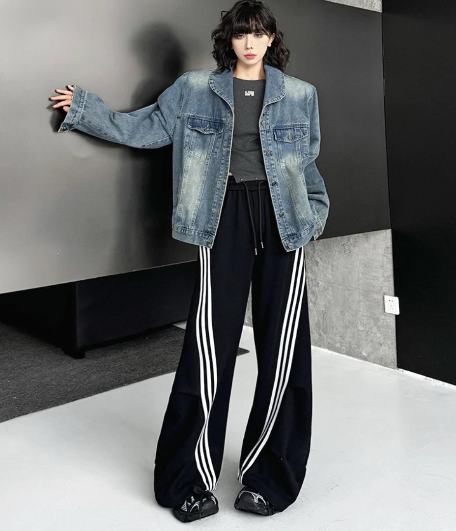 黒のスポーティーなワイドパンツを着用し、片腕を上げたダイナミックなポーズ。全身のシルエットを強調した一枚。