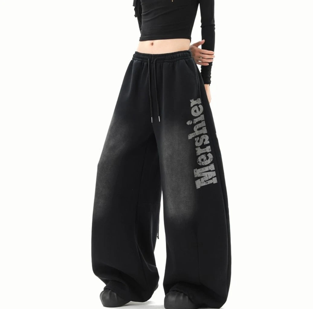 黒のワイドスウェットパンツを着用した斜め前からの全身写真。パンツのボリューム感とロゴを強調。