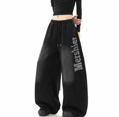 黒のワイドスウェットパンツを着用した斜め前からの全身写真。パンツのボリューム感とロゴを強調。