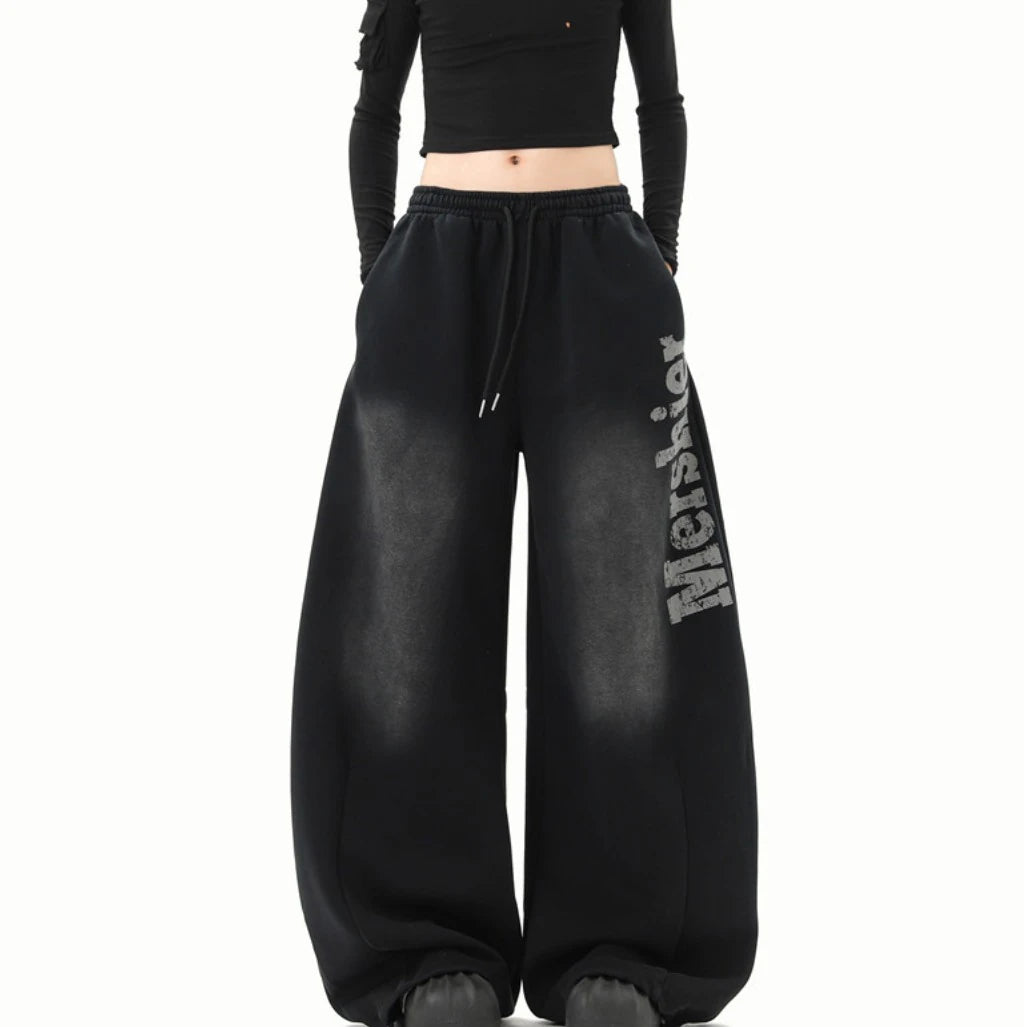 黒のワイドスウェットパンツを着用した全身正面。ウエストのドローコードとサイドの「Mershier」ロゴ。