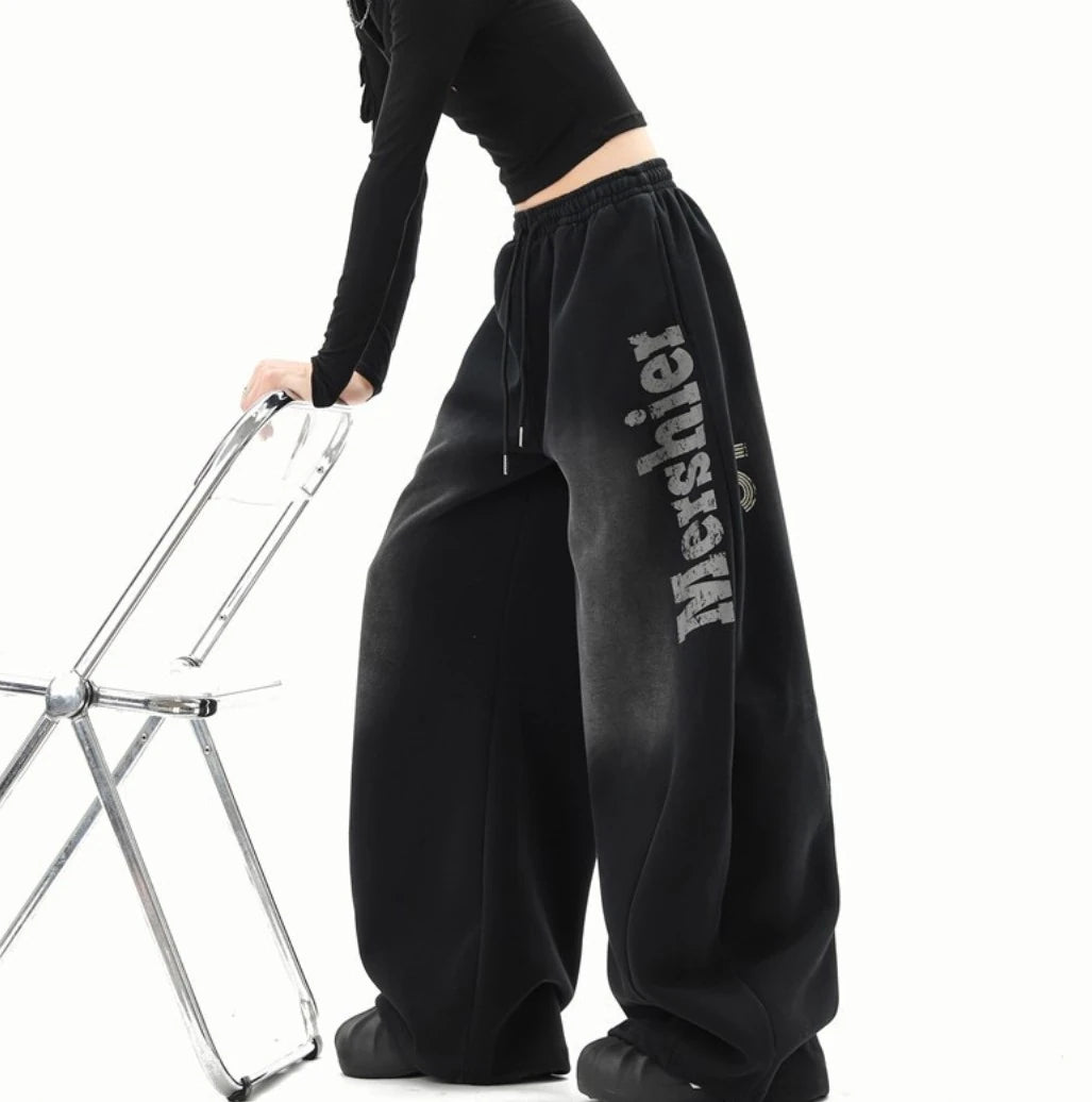 黒のワイドスウェットパンツを着用したサイドビュー。左太ももに「Mershier」ロゴが入った色落ち加工のデザイン。