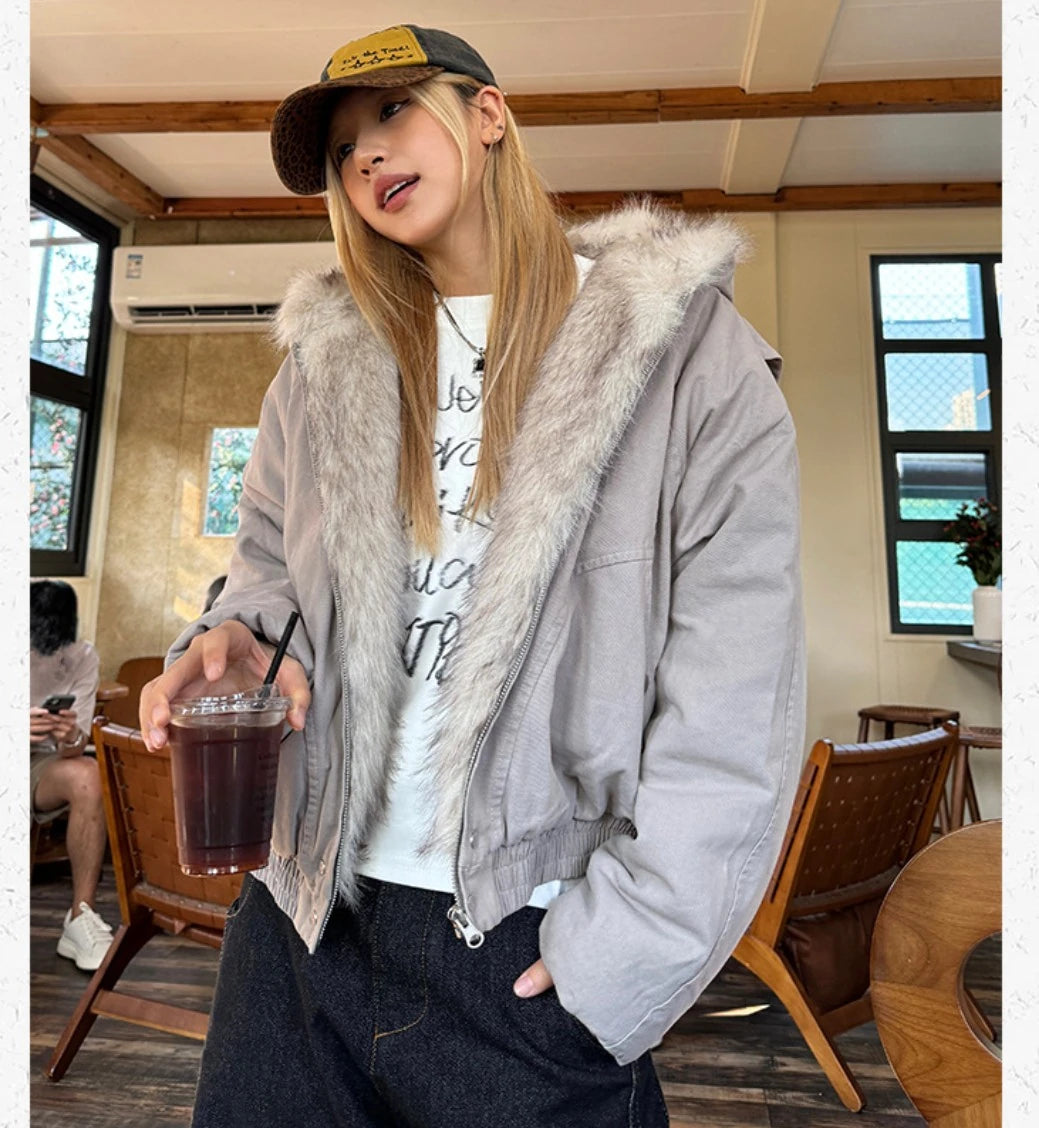 カフェの室内で、ブルゾンのジッパーを半開にしてインナーのTシャツを見せている女性。