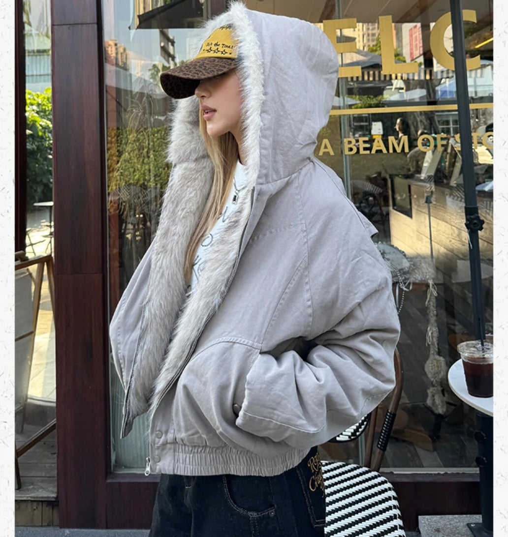 ファー付きのフードを被り、横向きで立ちポーズをとる女性。ブルゾンの袖のボリューム感がわかるカット。