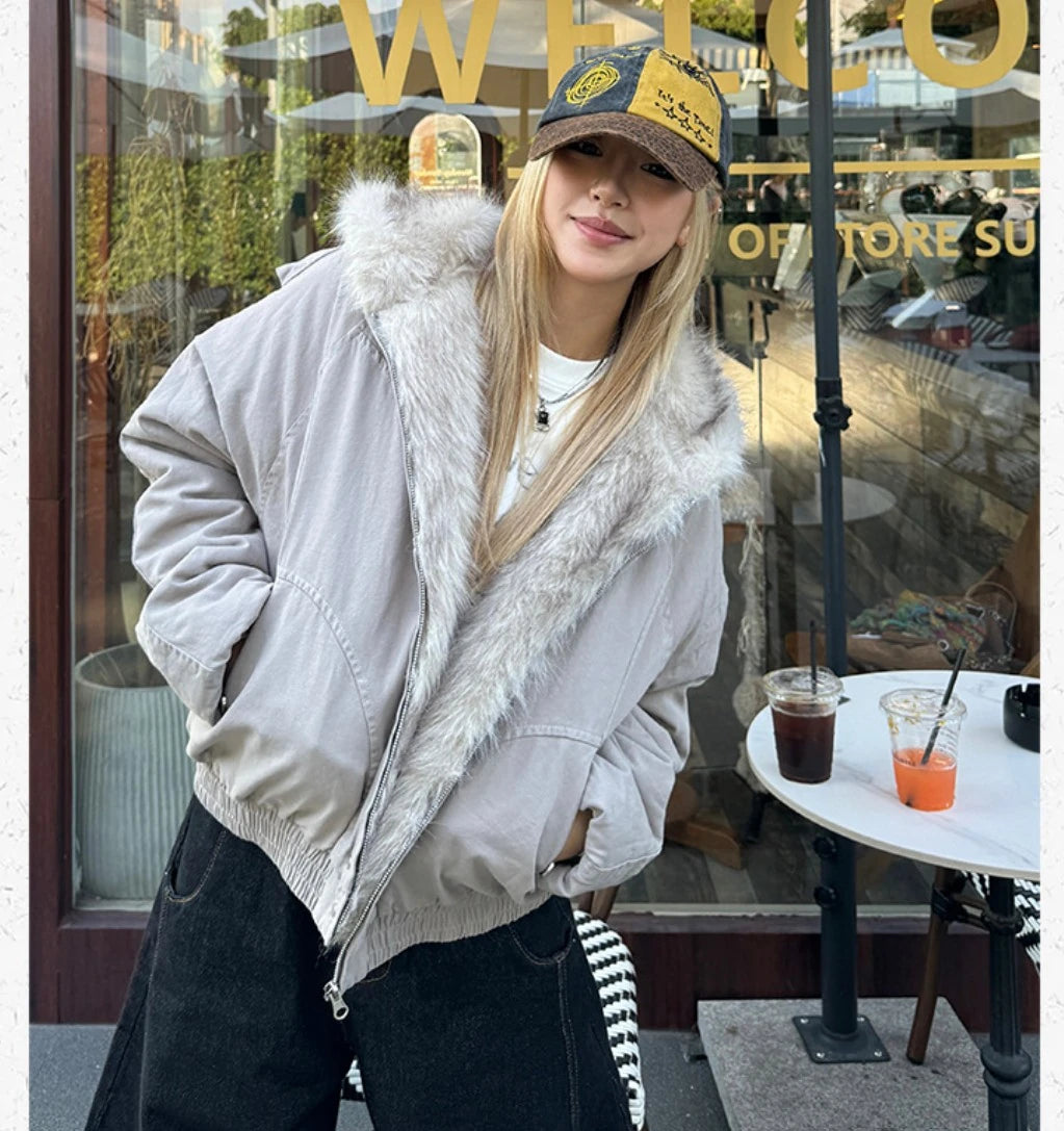 外のテラスで、こちらに微笑みかける女性。ボアとビッグシルエットが特徴のブルゾン。