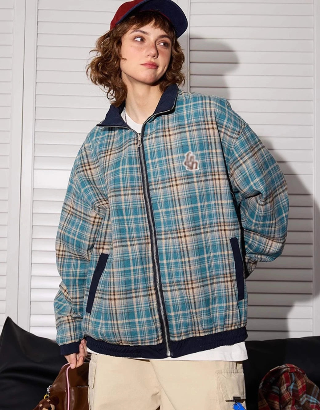 ブルーチェック柄側のリバーシブルジャケットを着たモデル。立ち姿、バッグ持ち