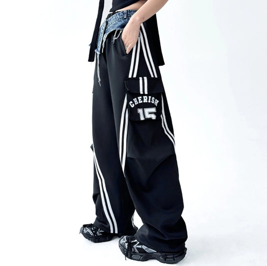 サイドの白ラインと「CHERISH 15」ロゴカーゴポケットが見える黒ワイドトラックパンツの横向きカット