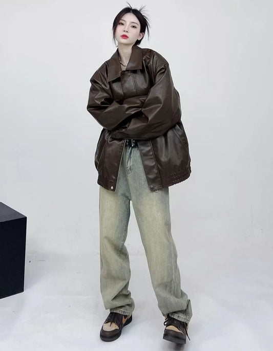 ブラウンのオーバーサイズレザージャケットと薄色ワイドジーンズ。ベルトでウエストマーク。
