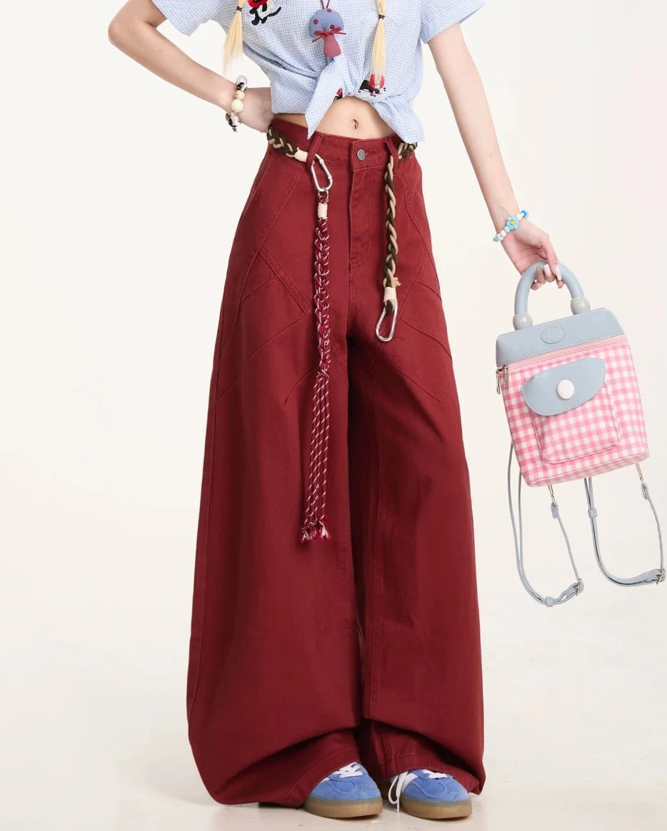 パンツの腰回りと太もも部分のクローズアップ。特徴的な切り替えラインと、手に持ったピンクのチェック柄バッグ。