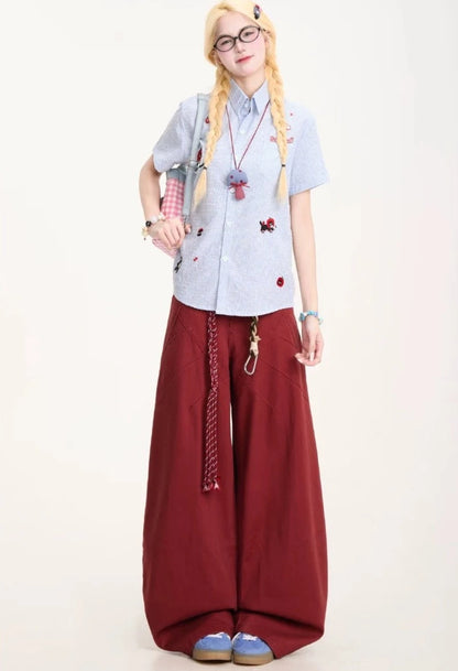 ワインレッドのワイドパンツを着用した全身正面。カーブを描くステッチデザインと、ボリュームのあるバルーンシルエット。