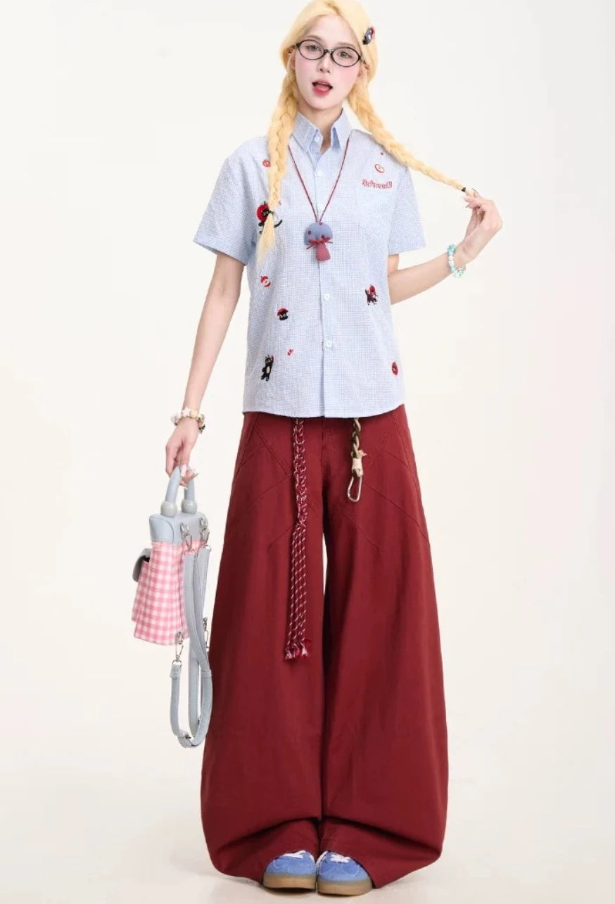 ワインレッドのワイドトラウザーを着用し、バッグを持ったポーズ。ゆったりとしたリラックス感のあるシルエット。