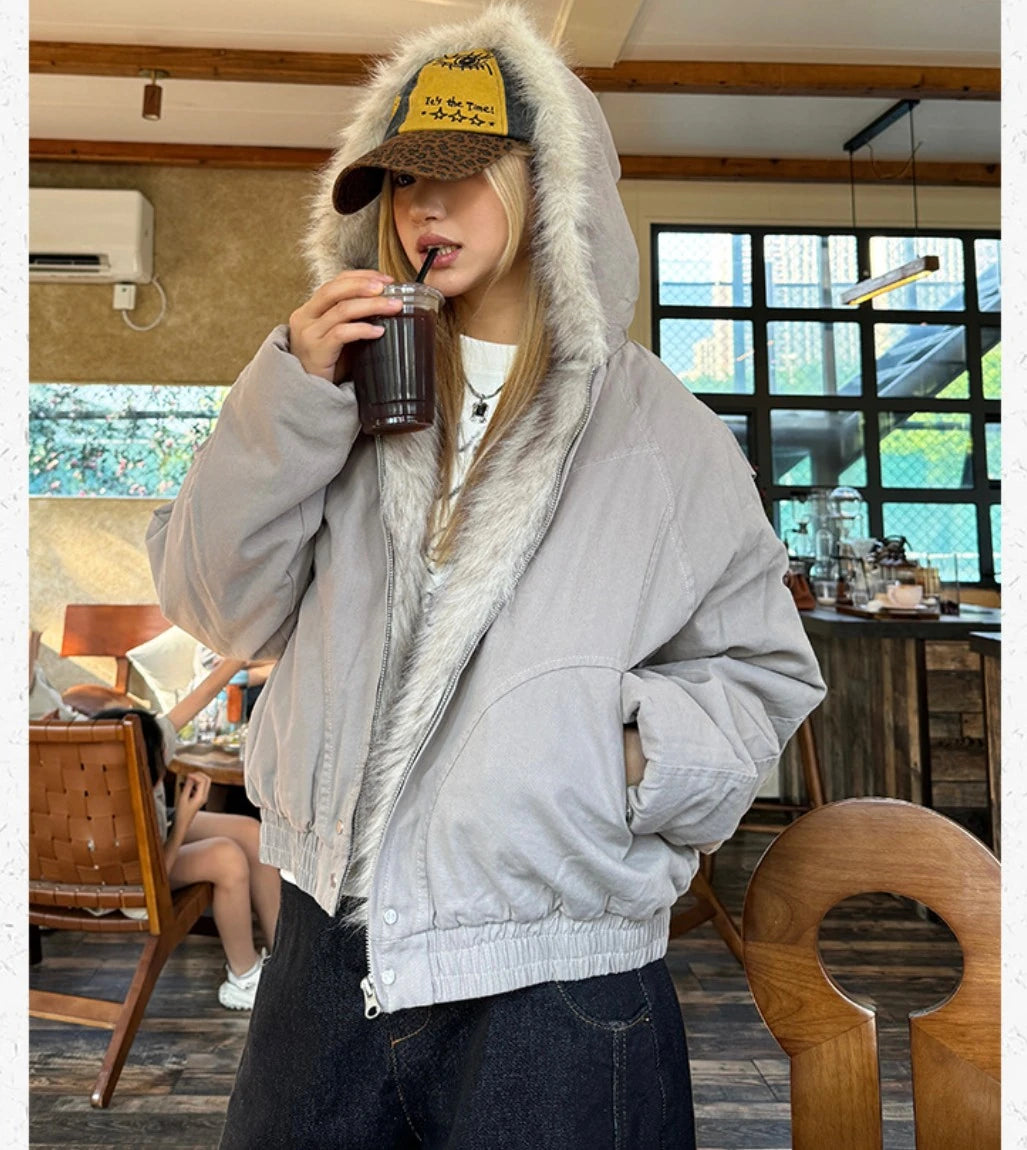 カフェの室内で、ブルゾンを着てアイスドリンクをストローで飲んでいる女性。