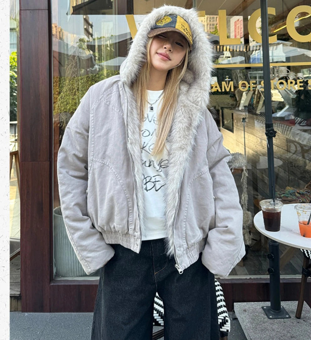 カジュアルなファー付きフードショートブルゾンを着用した女性の全身ショット。カフェの店先で撮影。